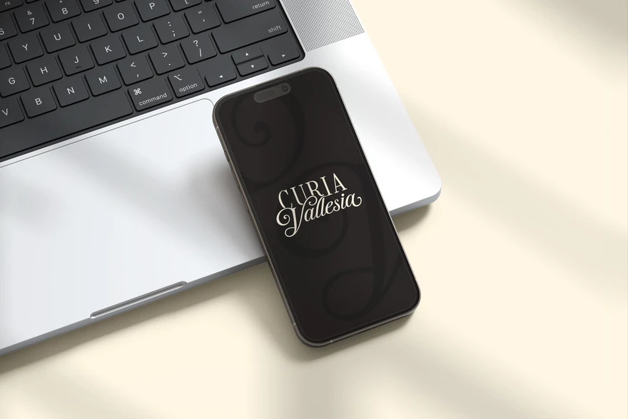 Curia Vallesia — Logo sur téléphone noir, posé sur ordinateur