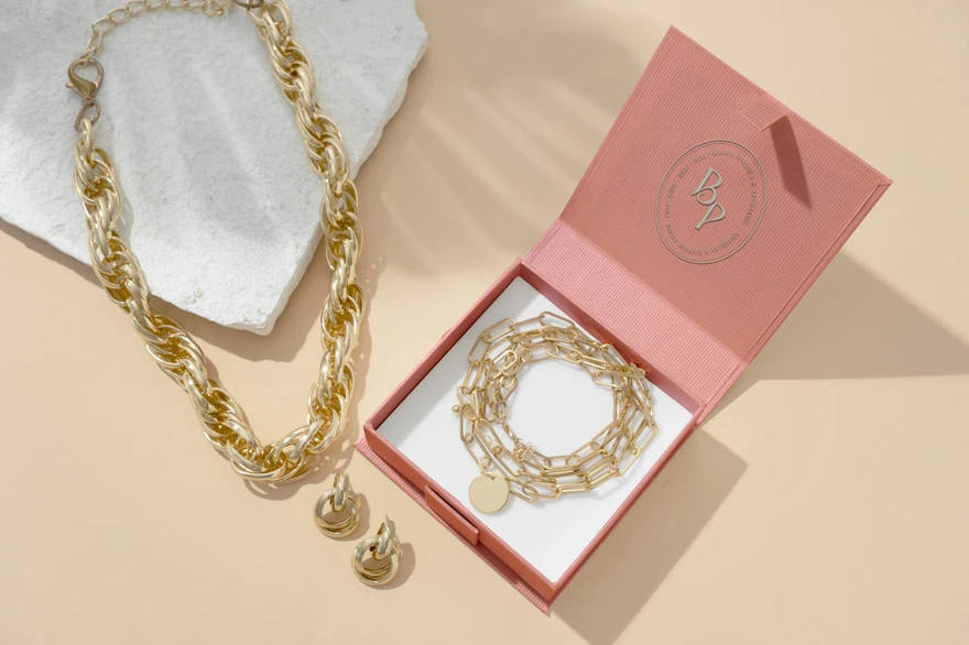 Brut | Poli — Écrin rose ouvert et collier doré